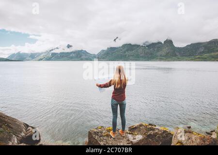 Woman looking at map planning vacation trip traveling solo in Norway active adventure lifestyle sea fjord and foggy mountains landscape Stock Photo