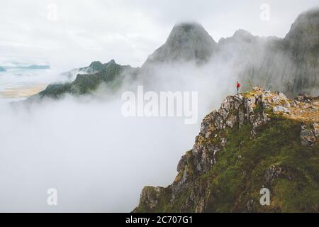 Man standing alone on mountain cliff edge foggy nature travel active healthy lifestyle outdoor adventure vacations in Norway Stock Photo