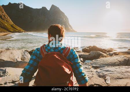 Man with backpack relaxing on Kvalvika beach enjoying ocean view travel lifestyle summer vacations outdoor solo trip in Norway Stock Photo