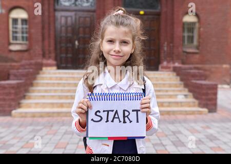 Elementary school girl student with notepad and handwritten word start Stock Photo