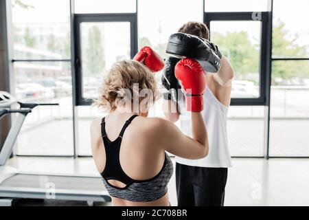 back view of sport couple in boxing gloves and pads exercising in gym Stock Photo