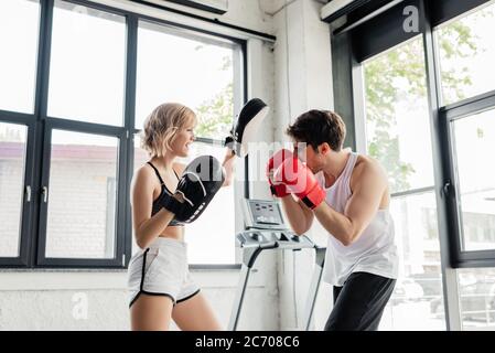 young sport couple in boxing gloves and boxing pads training in gym Stock Photo