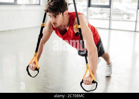 selective focus of handsome and athletic man working out with elastics in gym Stock Photo