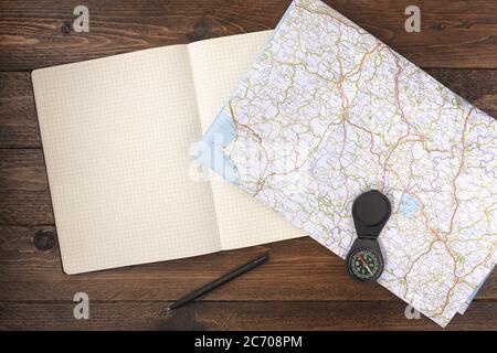Travel planning concept. Traveler accessories. Old vintage compass with blank notepad on wooden table background. Flat lay, top view. Stock Photo