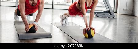 panoramic crop of sportive couple exercising with balls on fitness mats in gym Stock Photo