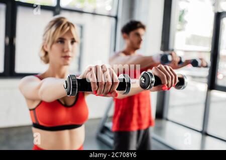 selective focus of sport couple working out with dumbbells in gym Stock Photo