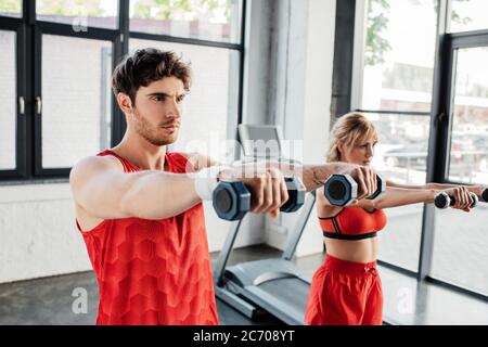 selective focus of man and woman working out with dumbbells in gym Stock Photo