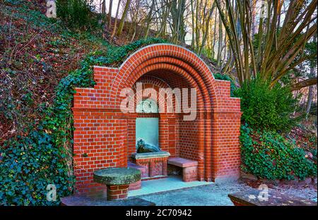 Elisabeth spring in the forest at Wiligrad Castle. Historic drinking fountain with red brick. Stock Photo