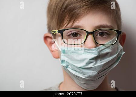 Childs face with glasses and disposable protective mask. Boy wearing mask protection against the flu. Stock Photo