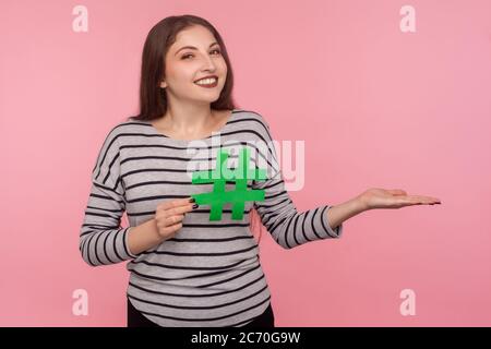 Follow trends, viral internet topic. Portrait of happy young woman in sweatshirt showing hashtag symbol and holding empty space for advertise text on Stock Photo