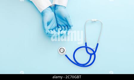 Doctor presenting empty hands, blank palm and stethoscope on blue color background. Doctor or nurse holding virtual object mockup. Health care Stock Photo