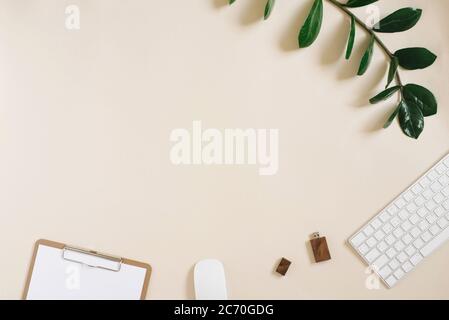 Modern desktop of a freelancer or blogger with a keyboard, mouse, pen, usb drive and Notepad with a blank sheet of paper on a light beige background w Stock Photo
