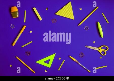 Stationery on purple. Bright stylish flat lay. Different yellow tools with copy space in centre. Stock Photo