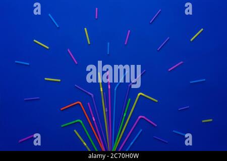 Multi-colored straws for drinking cocktail on blue background, holiday concept, top view. As firework. Stock Photo