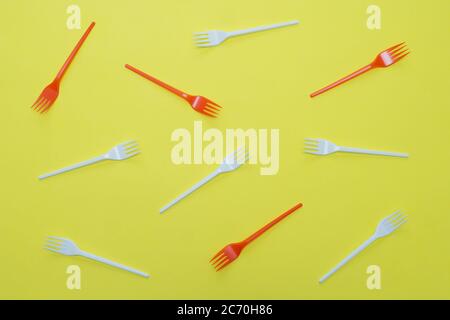 Plastic white and red forks on yellow background. Environmental concept. Flat lay. Stock Photo
