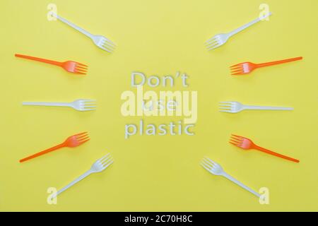 Plastic white and red forks on yellow background. Environmental concept. Don't use plastic lettering. Stock Photo