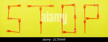 Word of stop from red disposable forks on yellow background. Web banner. Stock Photo