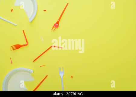 Plastic garbage on a yellow background. Disposable forks, plates, tubes. Copy space. Stock Photo