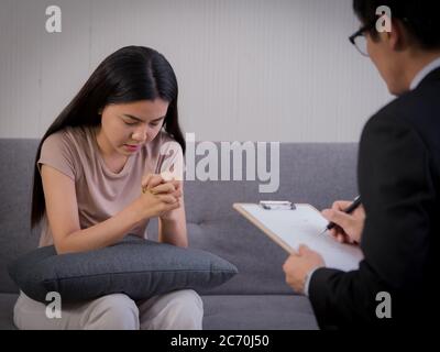 Sad woman with depression having consultation with psychiatrist in hospital mental health service center Stock Photo