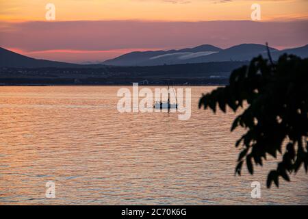 bright orange seascape at sunset, a pleasure yacht against the backdrop of the mountains of the resort city of Gelendzhik. Black sea coast Stock Photo