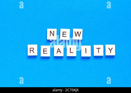 NEW REALITY. the words new reality are written in wooden letters on a blue background. top view. flat layout. Stock Photo