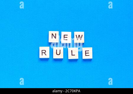 The NEW RULE is written in wooden letters on a blue background. New concept. Business, law, rules, update. tflat layout. op view. Stock Photo