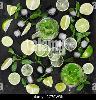 Tradition summer drink mojito with lime, mint and ice on black rustic surface. Top view.
