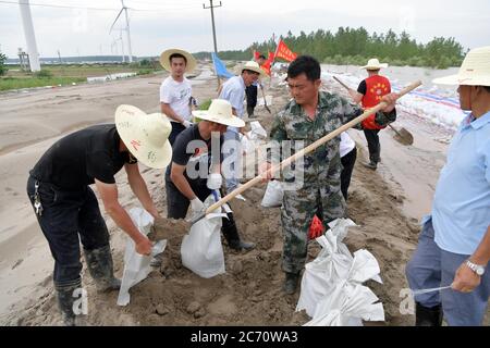(200713) -- NANCHANG, July 13, 2020 (Xinhua) -- Hong Mianxue (2nd R, front) and villagers pack sand bags in Jiangxinzhou islet of Jiujiang City, east China's Jiangxi Province, July 12, 2020. Hong Mianxue, 45, is the secretary of the Liuzhou village branch of the Communist Party of China. In this year's fight against the flood, he is responsible for the patrolling and protection of a section of the embankment of the Jiangxinzhou islet. As from July 3, Hong and villagers have been stick to their post day and night to protect the embankment and the islet. (Xinhua/Peng Zhaozhi) Stock Photo