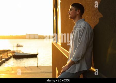 Young man stands leaning against a wall. Amazing sunset Stock Photo