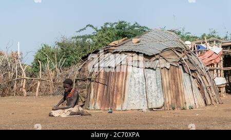 Omorate, Ethiopia - September 2017: Unidentified girl from Dassanech tribe sitting on soil ground , Ethiopia Stock Photo