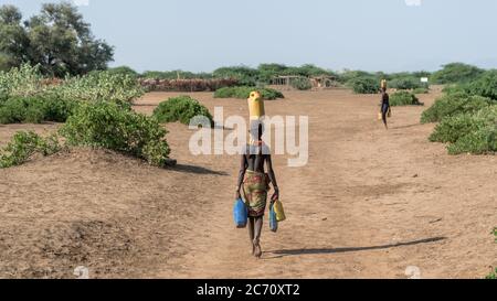 Omorate, Ethiopia - September 2017: Unidentified woman from Dassanech tribe carrying water to her village, Ethiopia Stock Photo