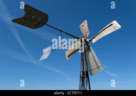 Simple metal windmill on strong tall legs against a clear blue sky Stock Photo