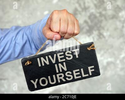 Hand holds a tablet Invest in yourself. Stock Photo