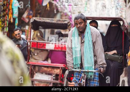New Delhi / India - February 18, 2020: Rickshaw carrying two Muslim women in narrow alley street of Old Delhi Stock Photo