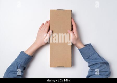 Child holds rectangular craft paper box on white background. Parcel delivery concept. Top view Stock Photo