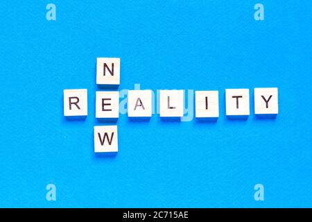 NEW REALITY. the words new reality are written in wooden letters on a blue background. crossword. Stock Photo