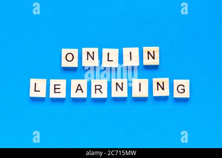 online learning concepts written in wooden letters on a blue background. a top view of a flat layout, online school. a new form of learning Stock Photo