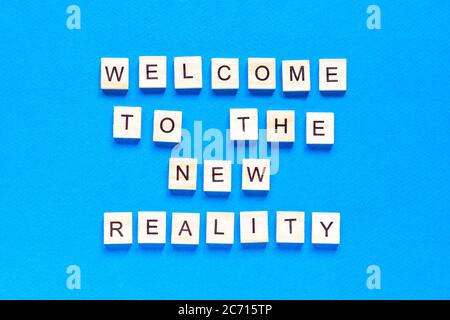 the inscription welcome to the new reality in wooden letters on a blue background. the view from the top. Modern technologies, a new device of the wor Stock Photo