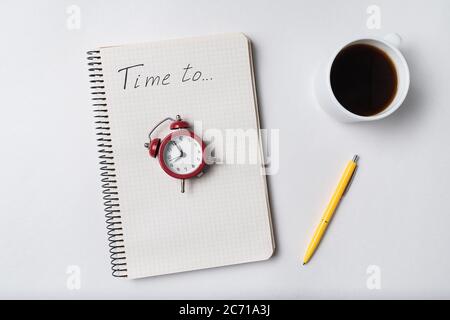 Notebook with inscription Time to. Notepad and vintage alarm clock. Planning and coffee Stock Photo