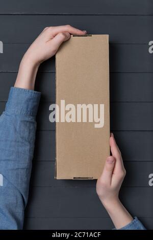 Craft rectangular box in children's hands on black background. Top view. Copy space Stock Photo