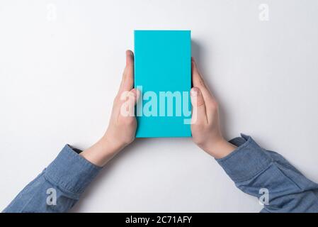 Child holds rectangular blue box on white background. Top view. Gift for child. Stock Photo