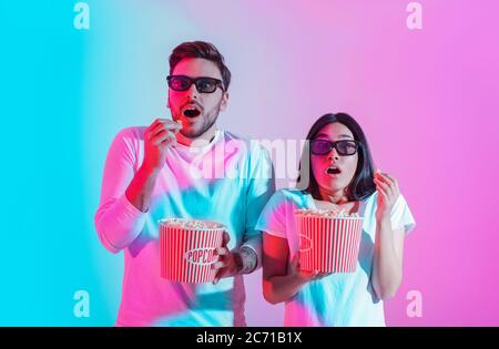 Special effects in movies. Surprised guy and girl with open mouths in 3D glasses are holding popcorn Stock Photo