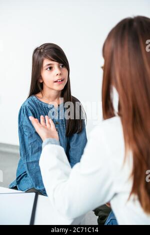 Doctor psychotherapist, therapist or pediatrician in white coat listens teen girl during reception at clinic. Teen problems, therapy session. Stock Photo