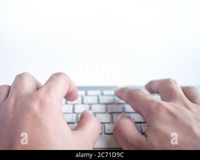 Close-up hands typing on remote control wireless computer keyboard isolated on a white background with copy space. Stock Photo