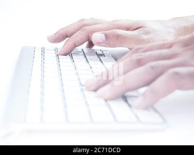 Close-up hands typing on remote control wireless computer keyboard on a white background. Stock Photo