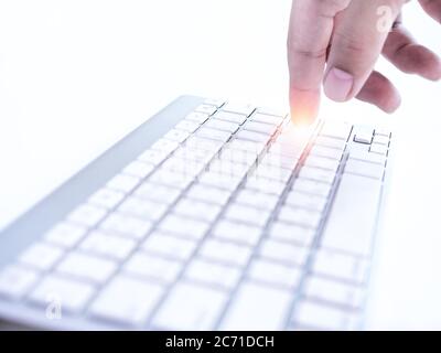 Finger pressing on enter button on remote control wireless computer keyboard on white background. Start working concept Stock Photo