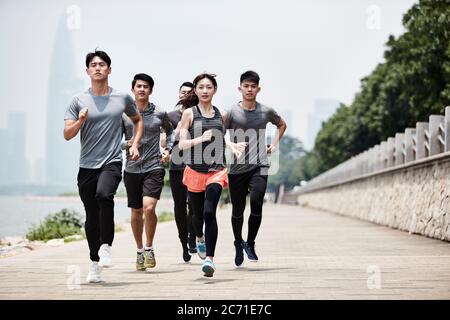 group of five young asian adult men and woman running training outdoors Stock Photo