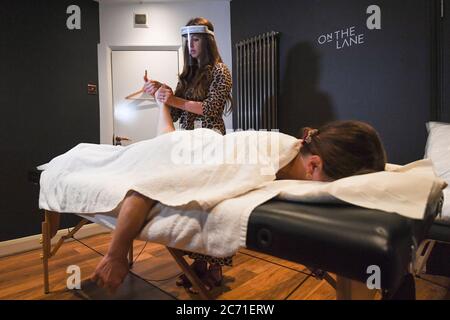 Facialist Taryn Williams massages client Annie Geurard at Taryn Aesthetics at On The Lane beauty salon in Belsize Park, London, as they reopen to customers following the easing of lockdown restrictions in England. Stock Photo