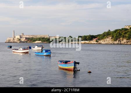 A view of rustic fishing boat at havana bay at sunset, morro lighthouse in the Havana Stock Photo