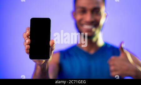Unrecognizable Black Sportsman Showing Smartphone Screen Gesturing Thumbs-Up In Studio